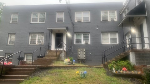 A grey building with a staircase leading to the front door.