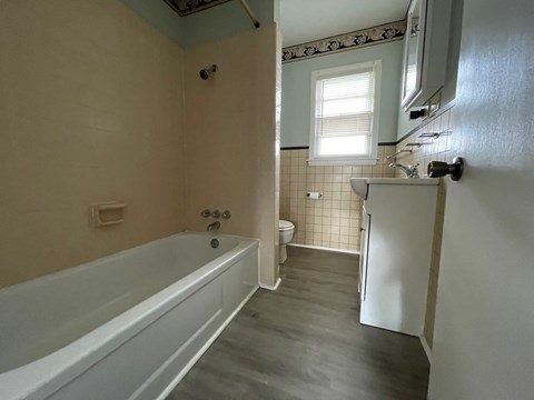 a bathroom with a tub and a sink and a refrigerator