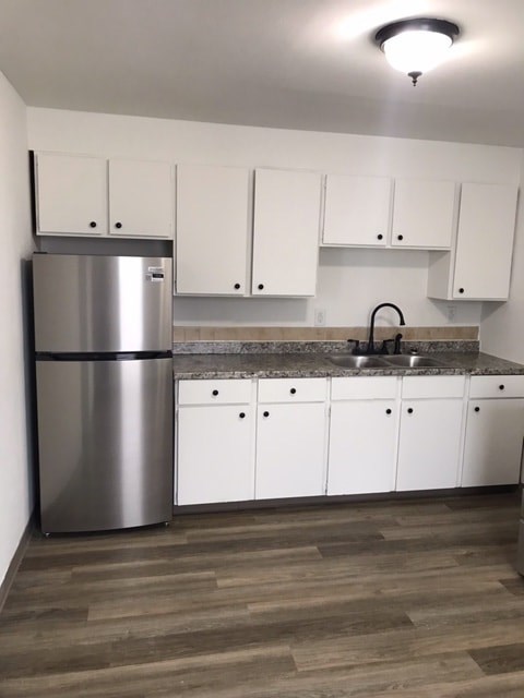 A kitchen with a stainless steel refrigerator and white cabinets.
