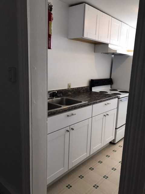 A kitchen with white cabinets and a black counter top.