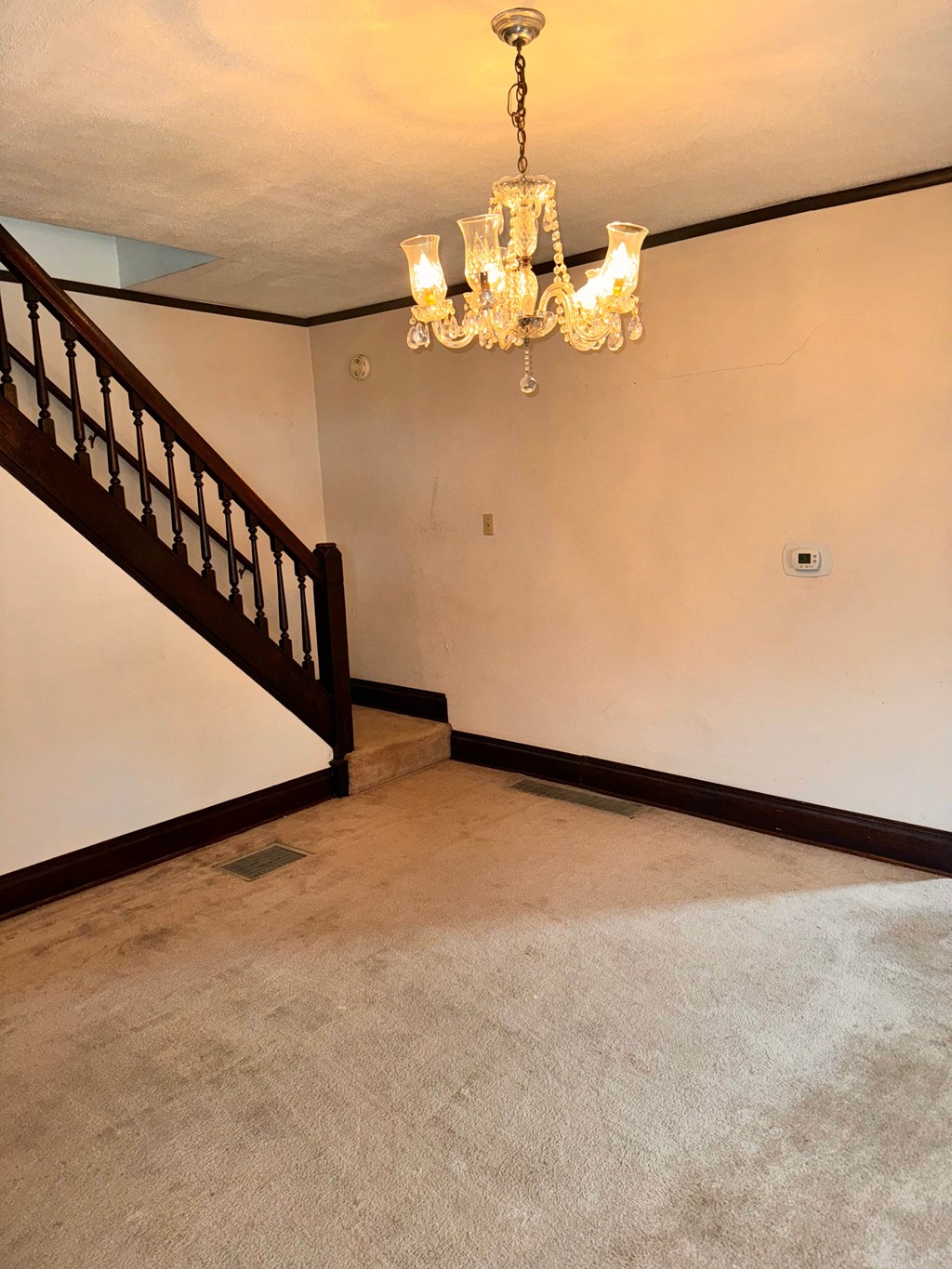 a empty living room with a chandelier and a staircase