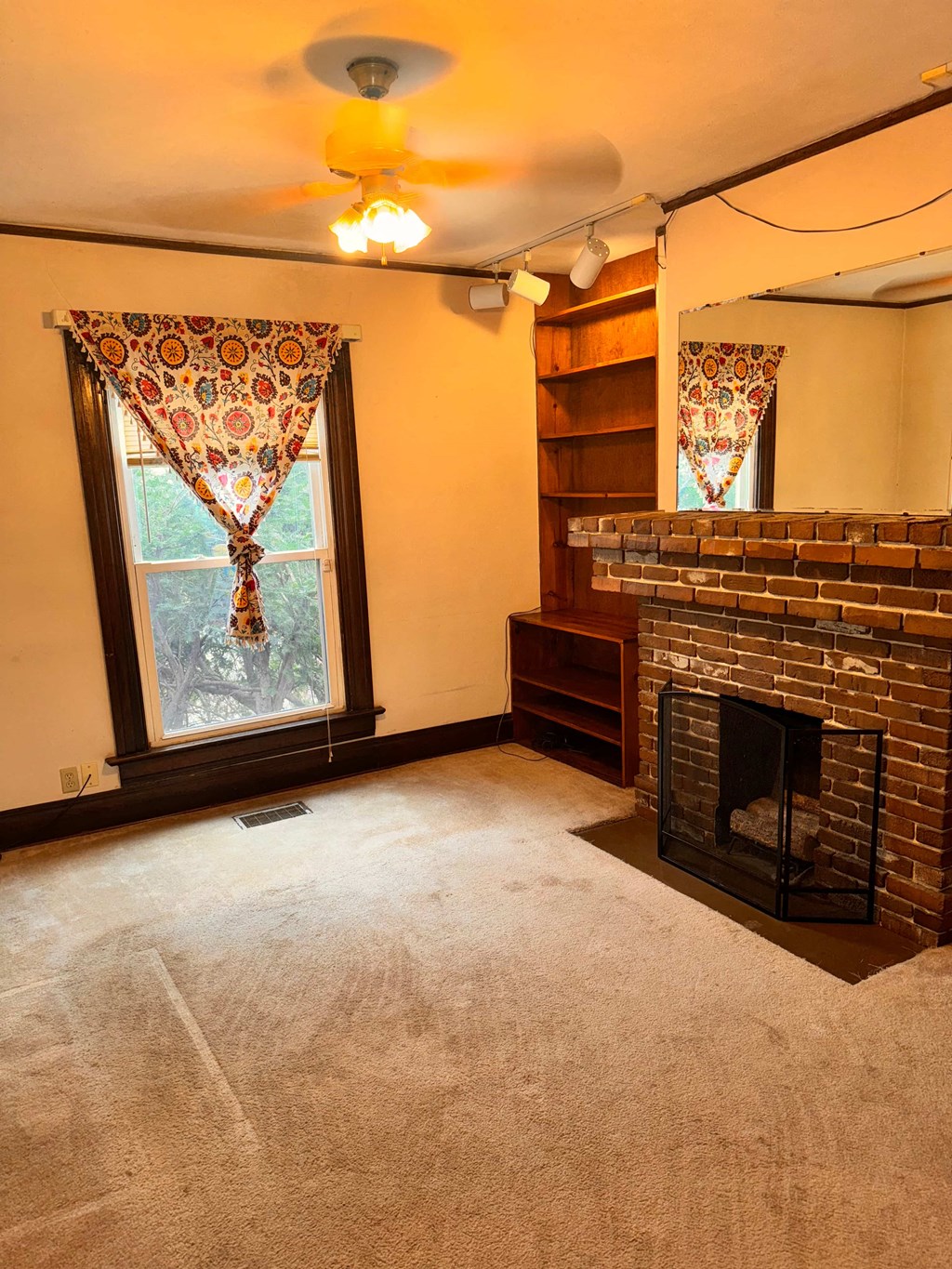 an empty living room with a fireplace and a window