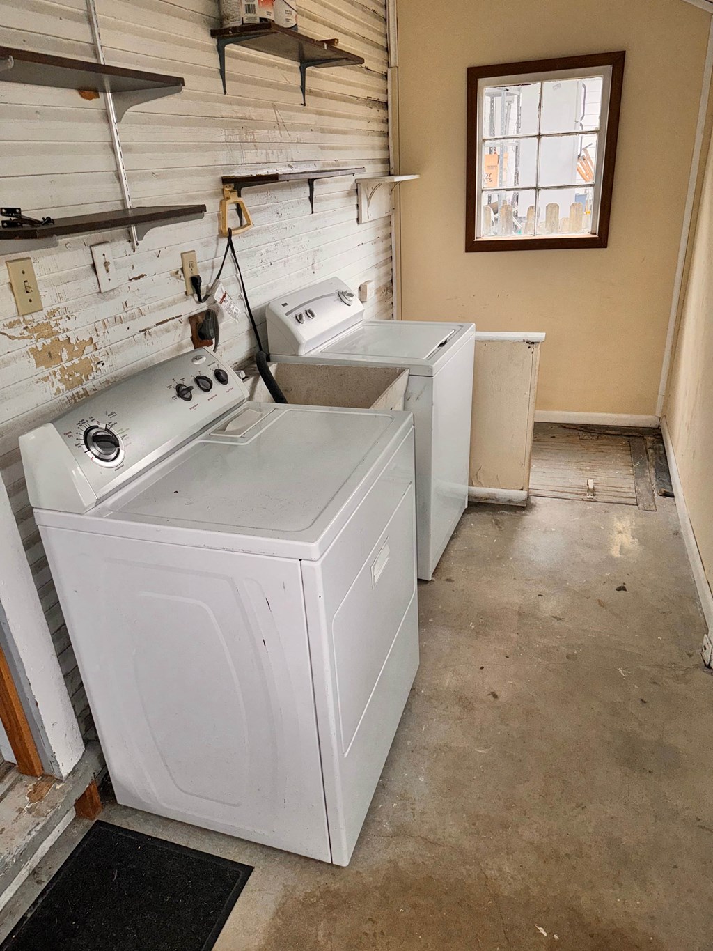 two washers and a dryer in an empty laundry room