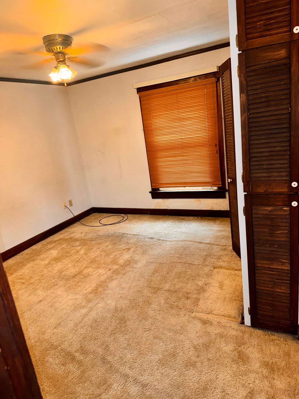 an empty living room with a ceiling fan and a window