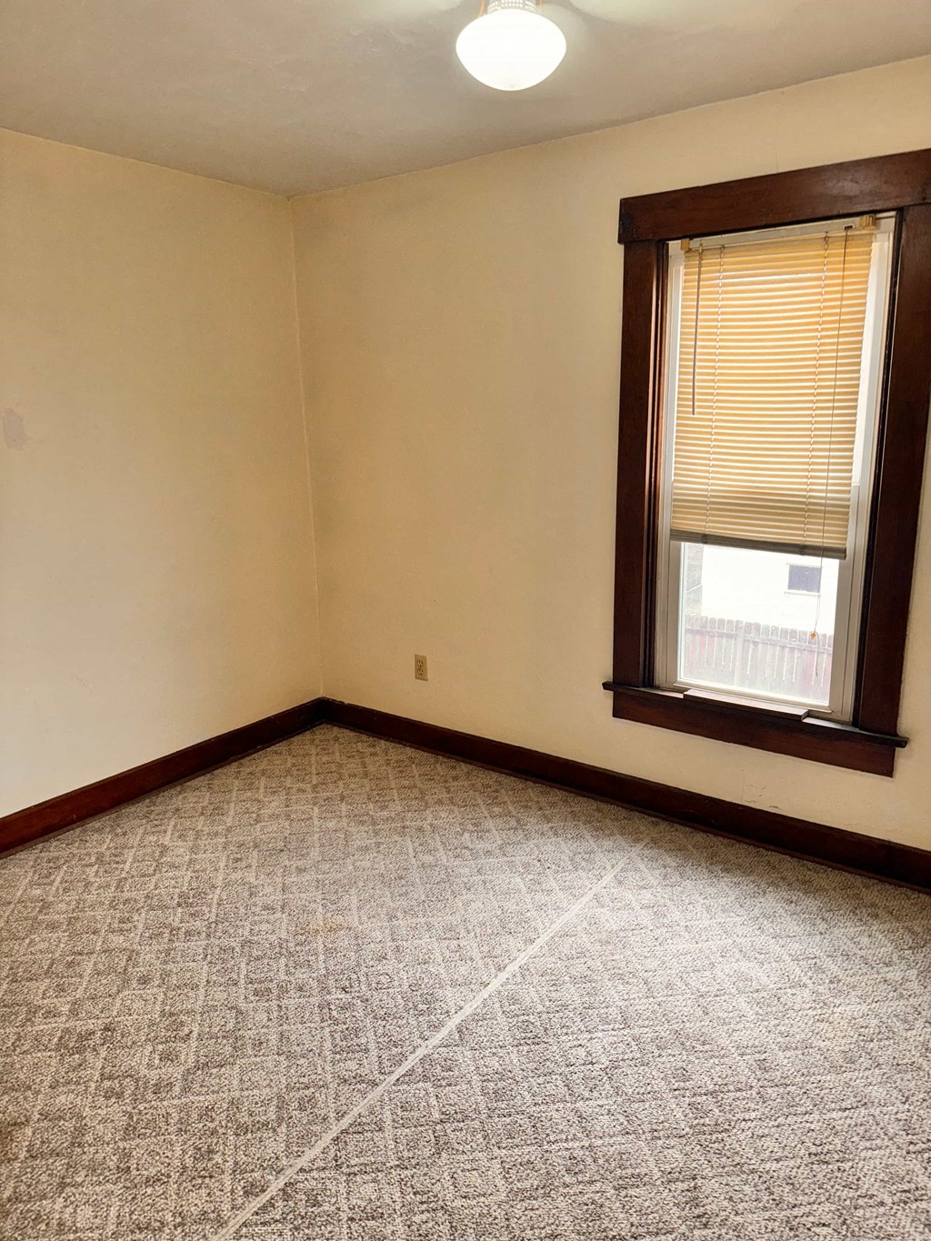 an empty room with a window and a carpeted floor