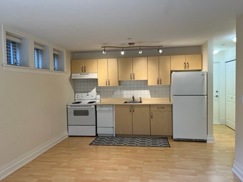 an empty kitchen with white appliances and wooden floors