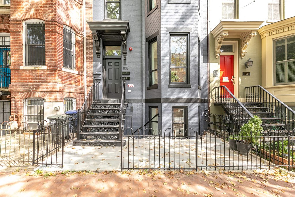 the front of a house with stairs and a red door
