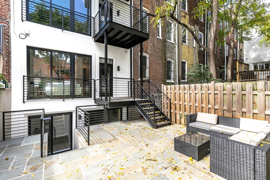 the backyard has a patio with a fence and a balcony
