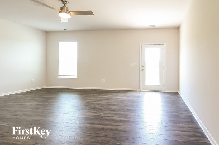 an empty living room with wood floors and a ceiling fan