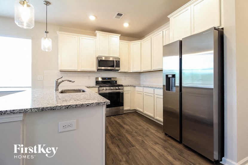 a kitchen with white cabinets and stainless steel refrigerator