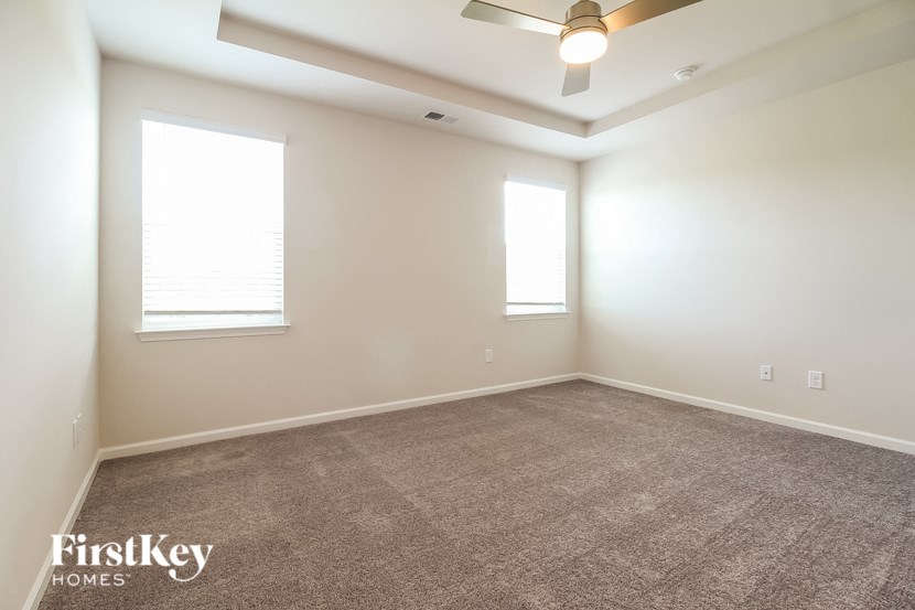 an empty living room with a ceiling fan and two windows