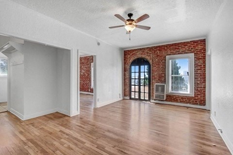 an empty living room with a brick wall and a ceiling fan