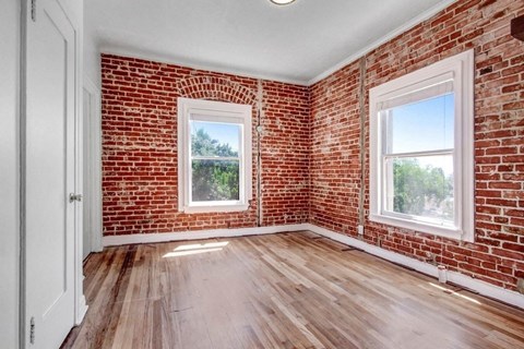 an empty room with a brick wall and wooden floors