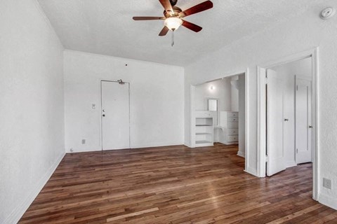 an empty living room with white walls and a ceiling fan