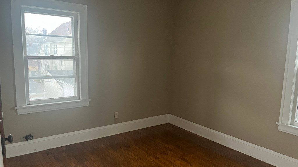 an empty room with wooden floors and a window
