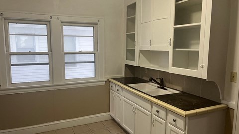 a kitchen with white cabinets and a sink and window