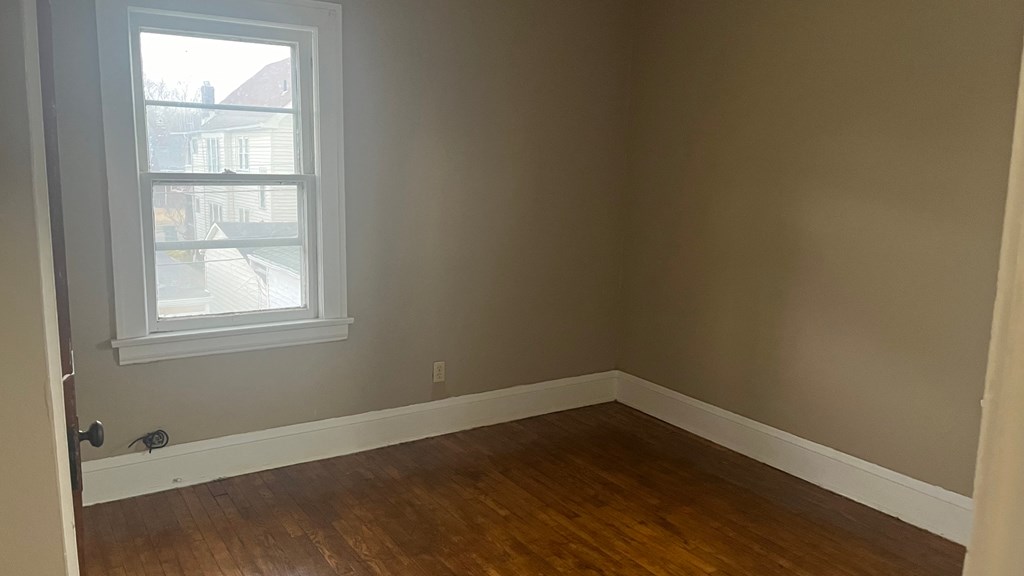 an empty room with wooden floors and a window