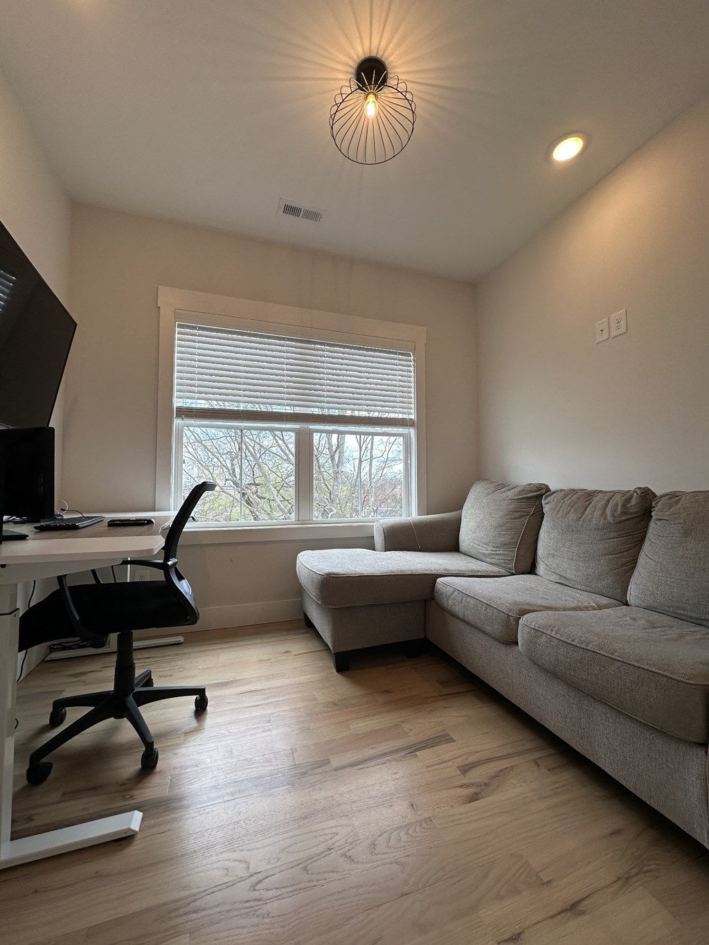 a living room with a couch and a desk and a window