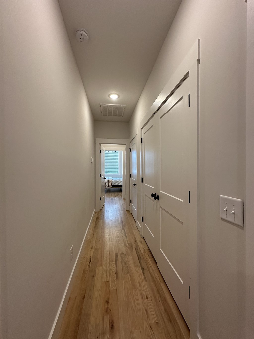 a long hallway with wooden floors and white doors