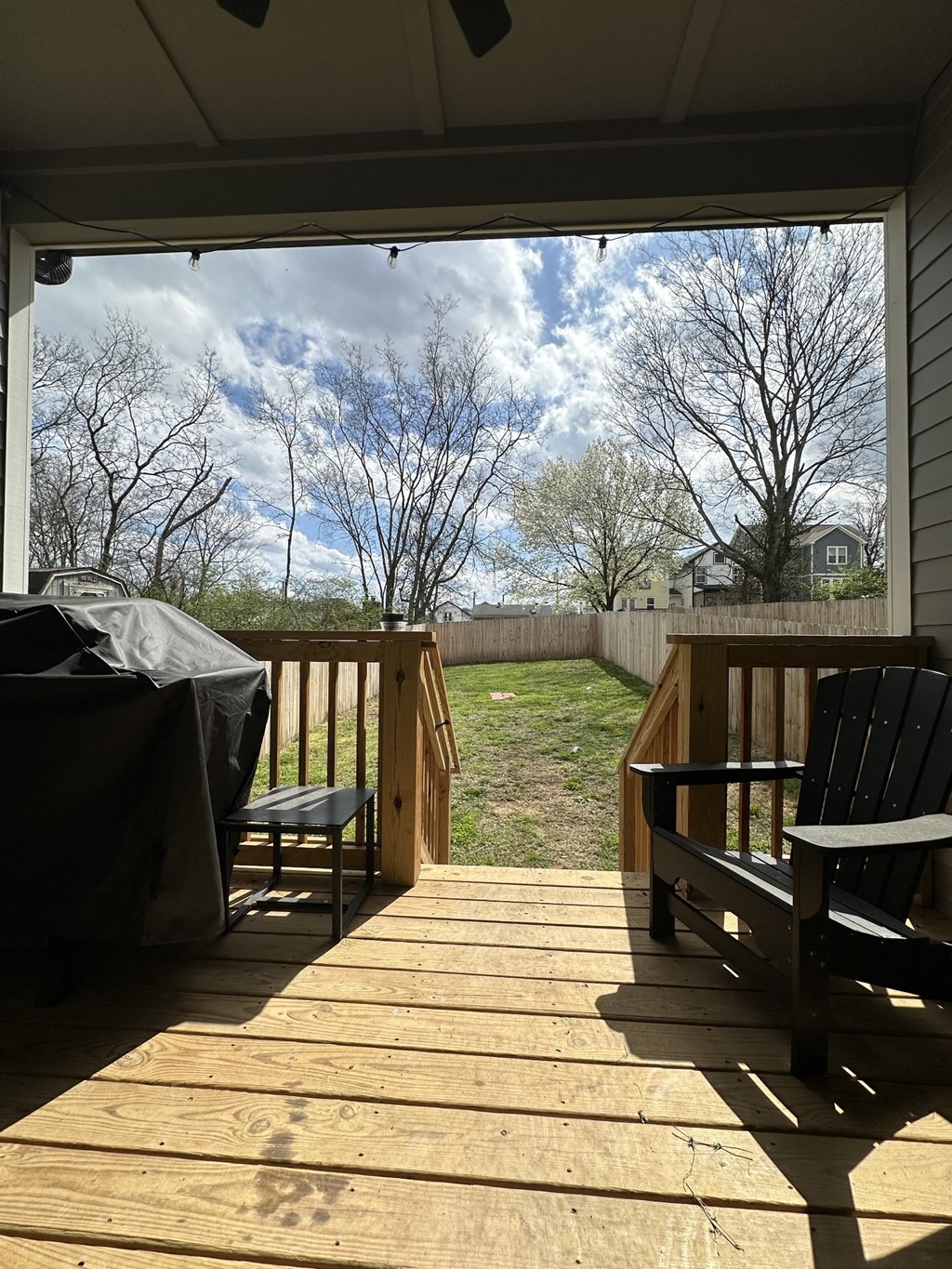 a deck with two chairs and a view of a yard and the sky
