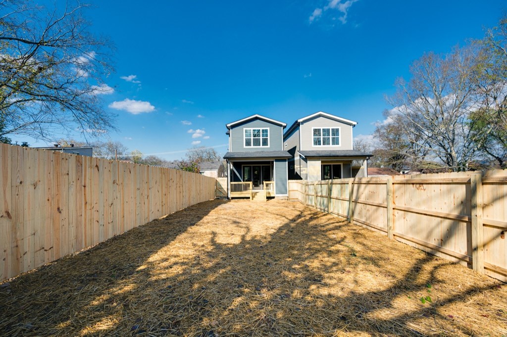 a house with a wooden fence and a yard with a house behind it