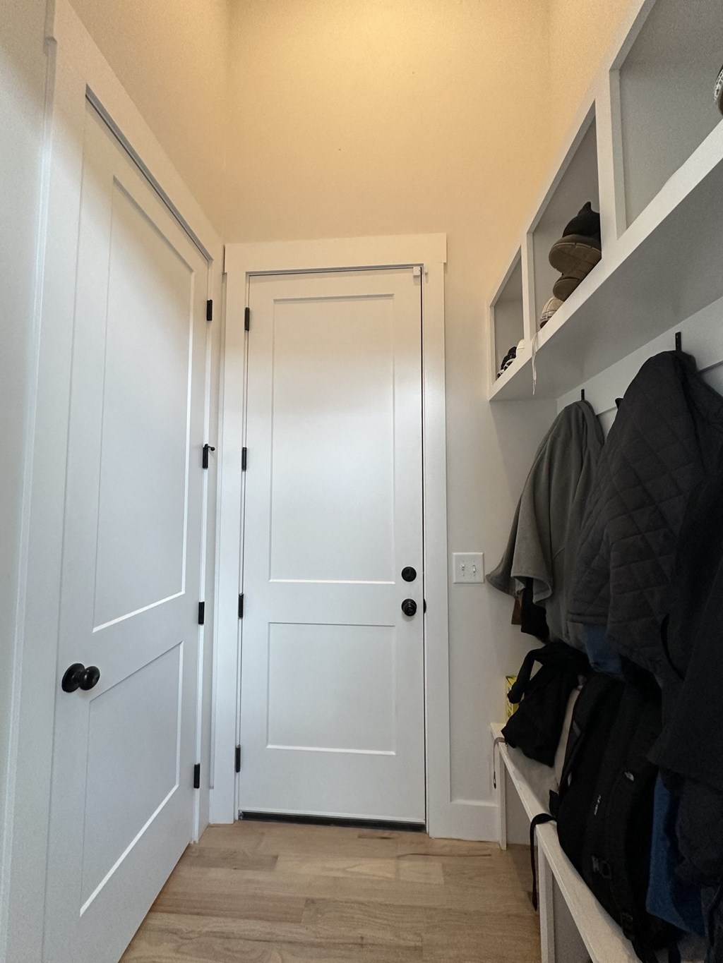 a hallway with white doors and a closet with clothes hanging