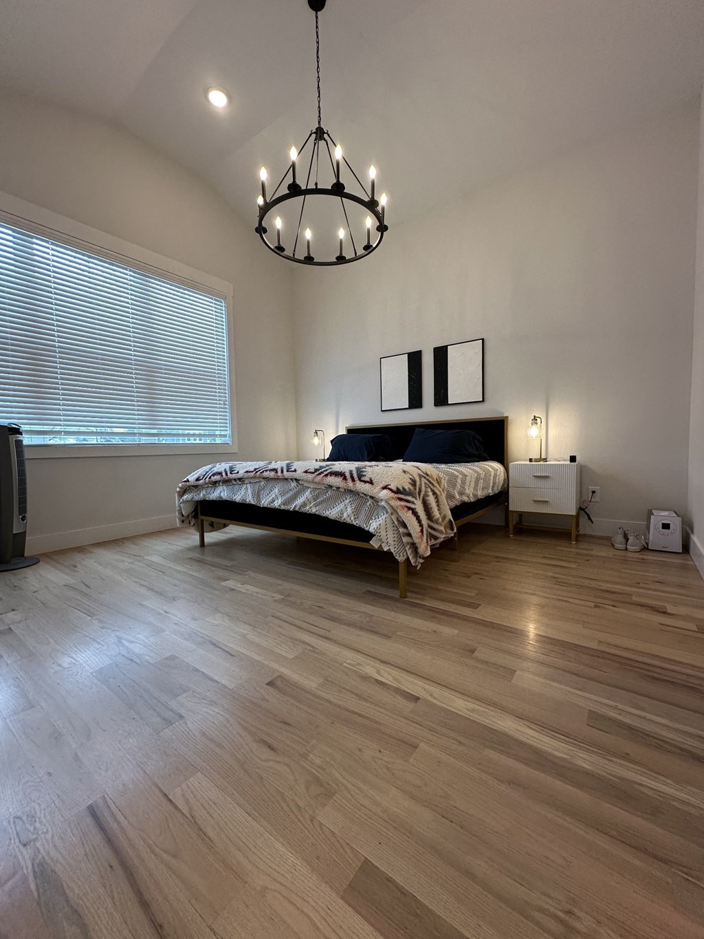 a bedroom with a bed and a large window and a wooden floor