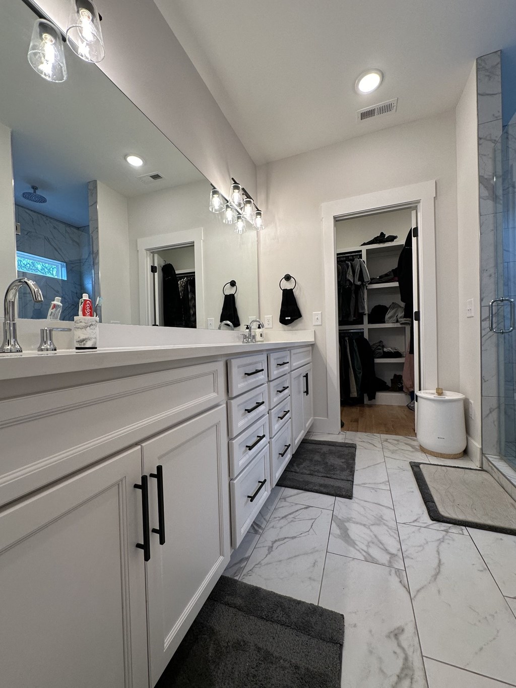 a large white bathroom with double sinks and a shower