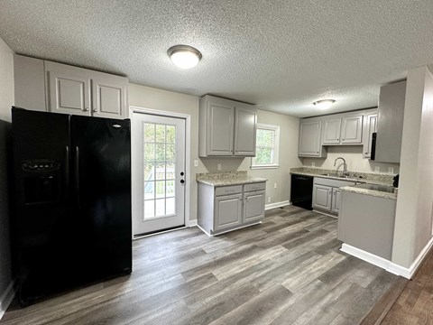 a kitchen with white cabinets and a black refrigerator