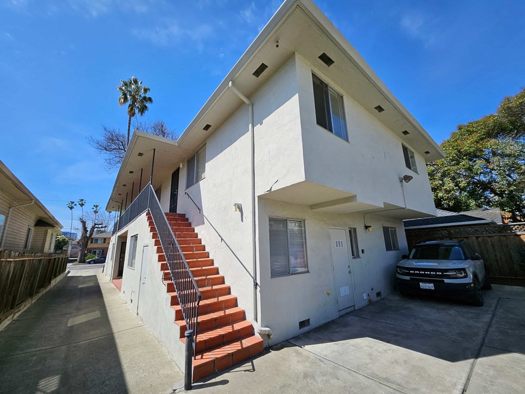 a white house with stairs and a car parked in front of it