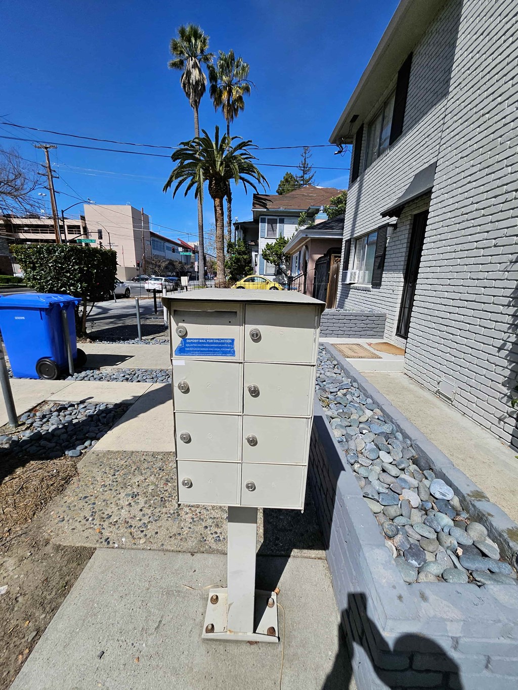 a mail box on the sidewalk in front of a house