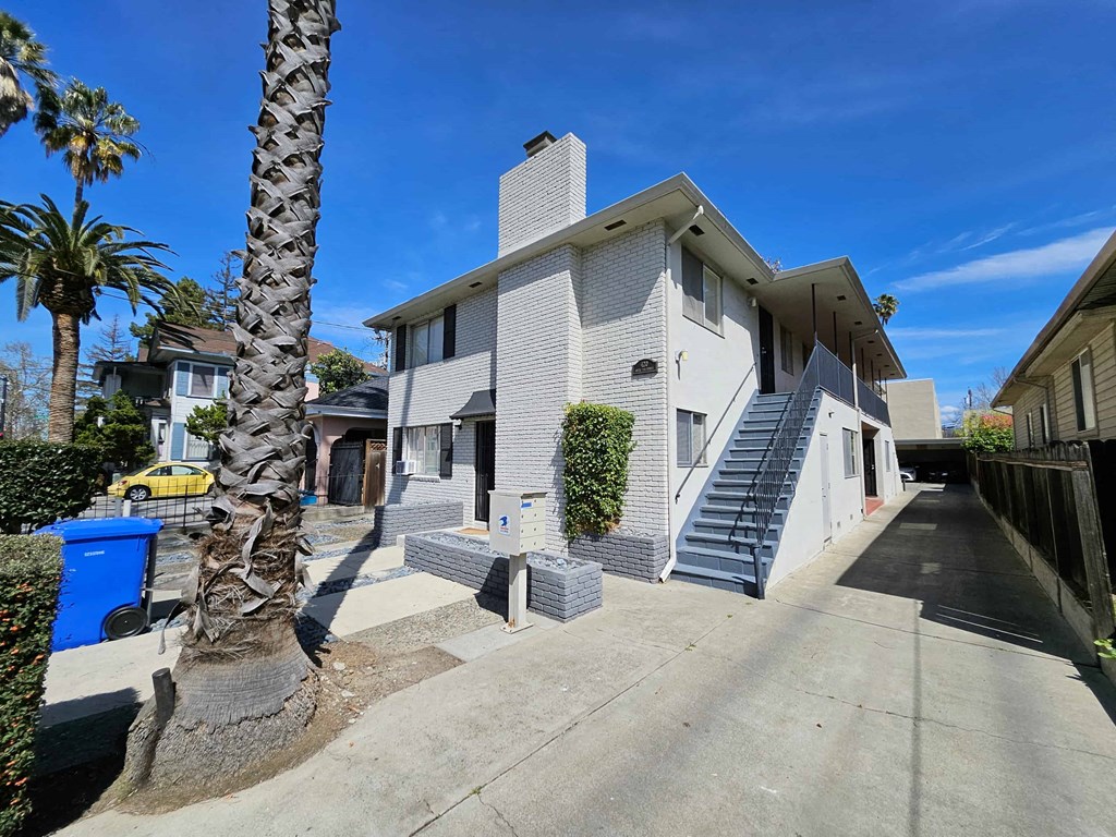 the front of a white house with stairs and palm trees
