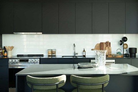 a kitchen with a marble counter top and black cabinets
