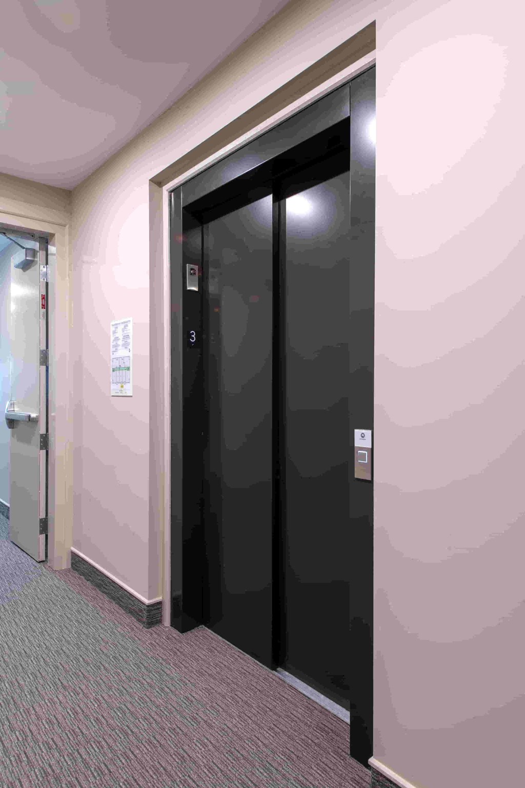 a pair of black doors in a hallway with a carpeted floor