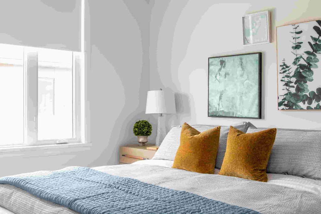 a bedroom with a bed with pillows and pictures on the wall