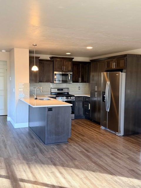 A modern kitchen with dark wood cabinets and stainless steel appliances.