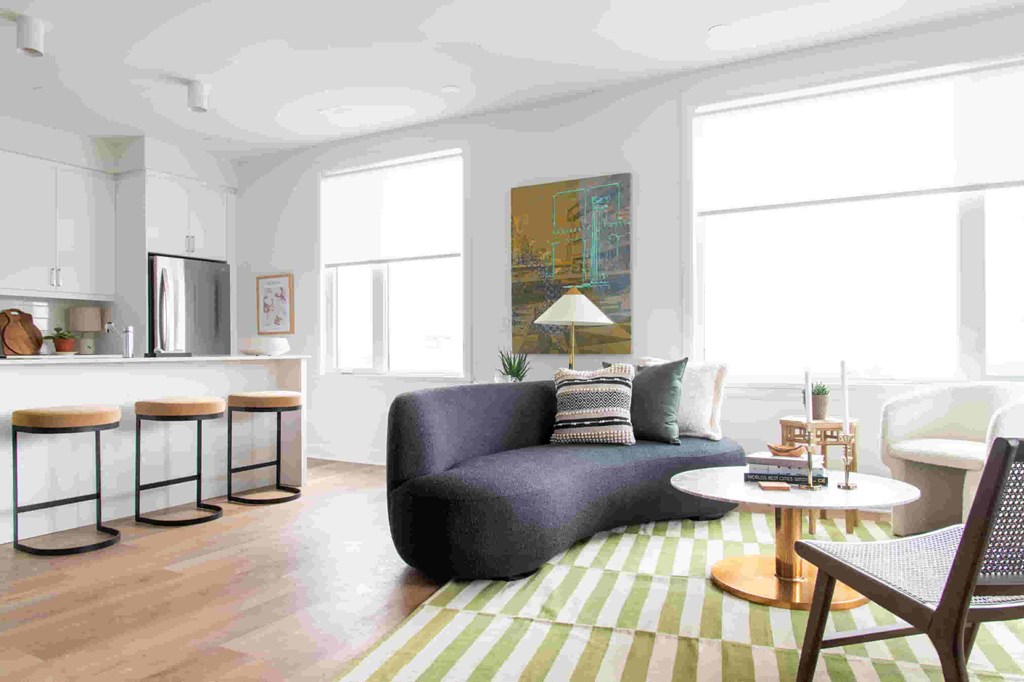 a living room with a blue couch and a yellow and white striped rug