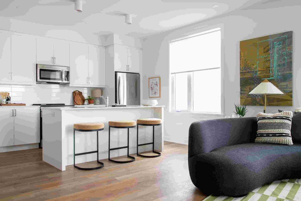 an open kitchen and living room with a couch and bar stools