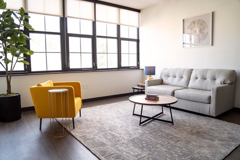 A living room with a yellow chair, a grey sofa, and a coffee table.