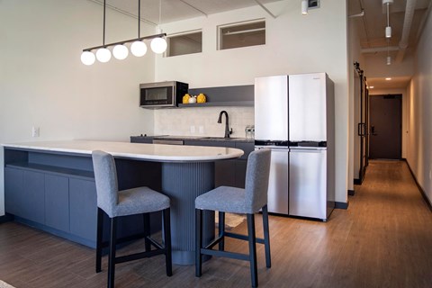 A kitchen with a white countertop and grey chairs.