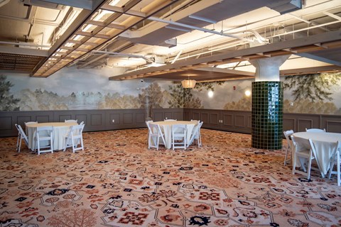 A room with tables and chairs and a mural on the wall.