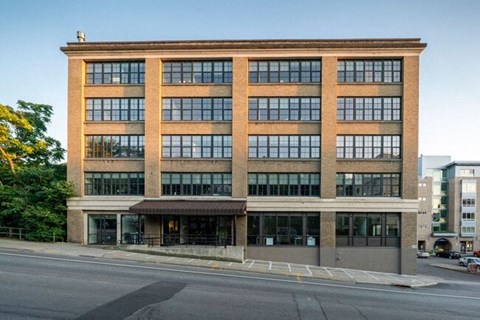 A large brick building with many windows is situated on a street corner.