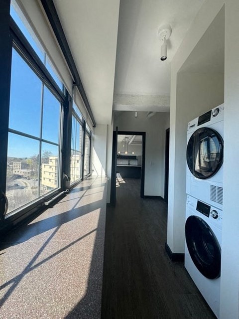 A long hallway with a washing machine on the right.