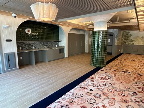 A room with a floral carpet and a green tiled column.