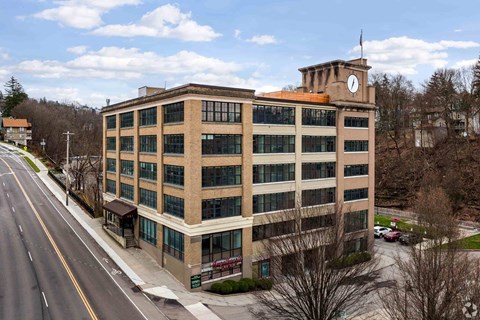 A large building with a clock tower on the roof is situated on a street corner.
