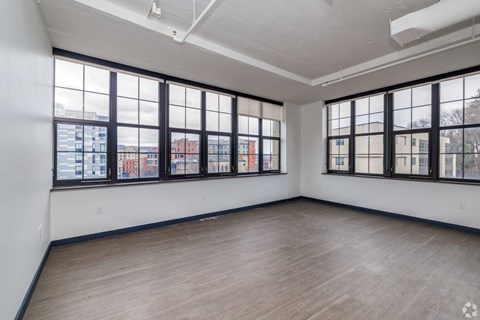 Empty room with large windows overlooking a cityscape.