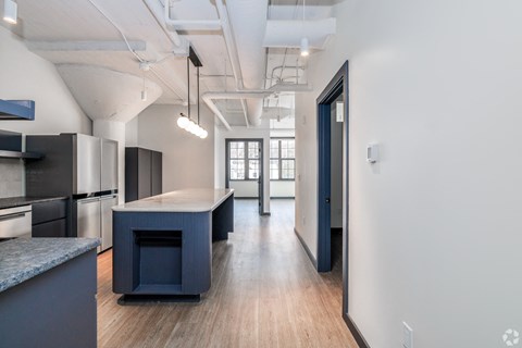 A modern kitchen with dark blue cabinets and a wooden floor.
