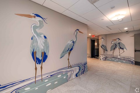 A room with a mural of three birds on the wall.