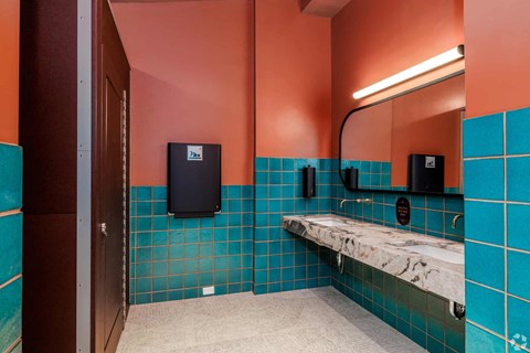 A bathroom with a blue tiled wall and a white bench.