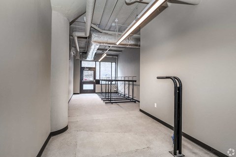 A long hallway with a black railing and a white wall.